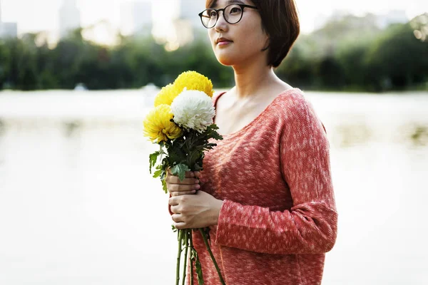 Asiatisk tjej håller blommor — Stockfoto