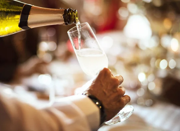 Číšník nalévá šampaňské do sklenice — Stock fotografie