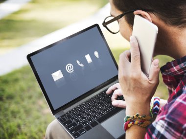 Dizüstü bilgisayar kullanarak ve cep telefonunuza konuşan adam