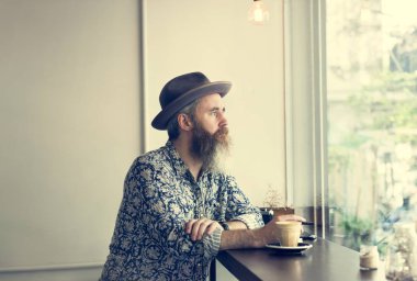 hipster adam kafede oturan şapkalı