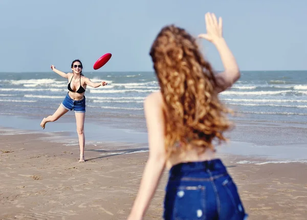 Girls playing frisbee on beach — Stock Photo, Image