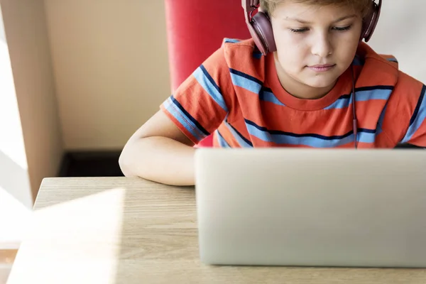 Niño en auriculares usando el ordenador portátil —  Fotos de Stock