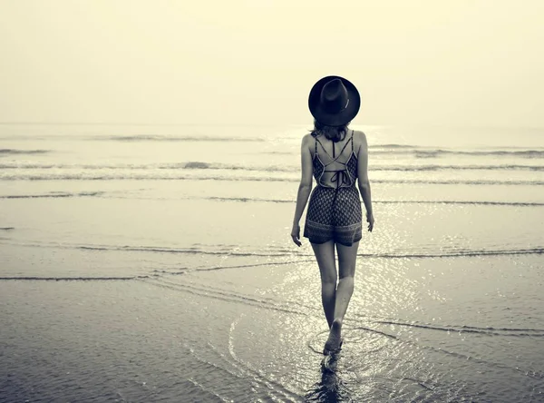 Женщина в шляпе, идущая к океану — стоковое фото