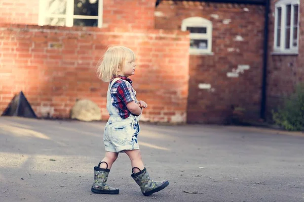 Niedliches Kind, das in Gummistiefeln läuft — Stockfoto