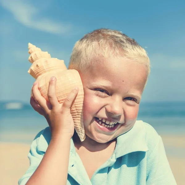 Pequeno menino ouvindo shell — Fotografia de Stock