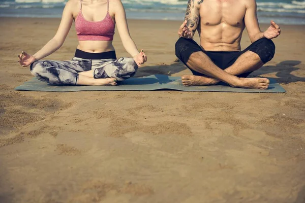 Koppel doen yoga op het strand — Stockfoto