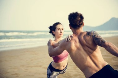 Çiftler plajda yoga yapıyor.
