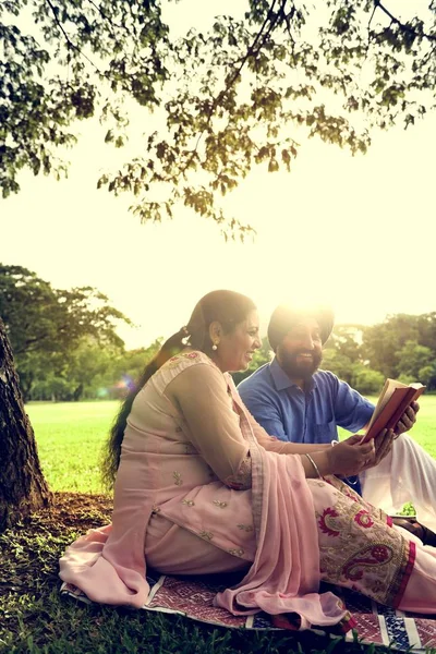 Indiska par läsning i park — Stockfoto
