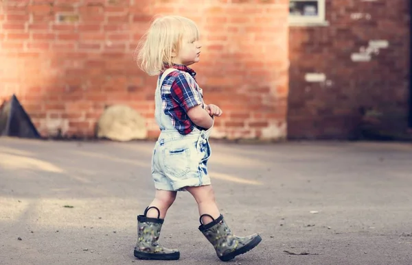 Cute kid spaceru w gumowe buty — Zdjęcie stockowe