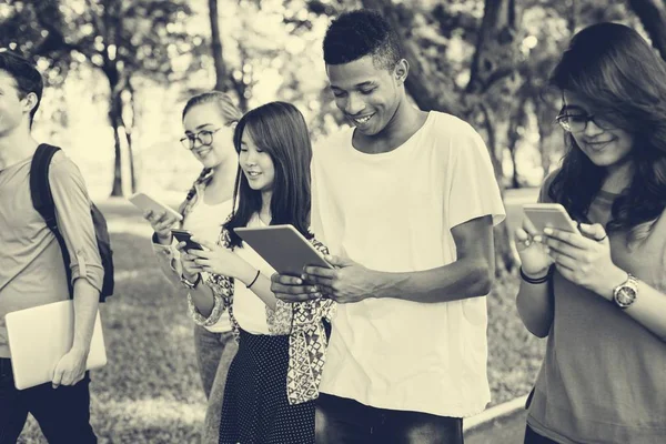 Jovens Caminhando com aparelhos digitais — Fotografia de Stock