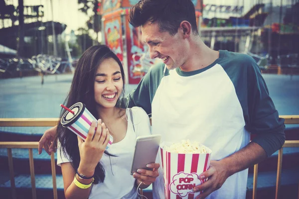 Pareja usando móvil en parque de atracciones — Foto de Stock