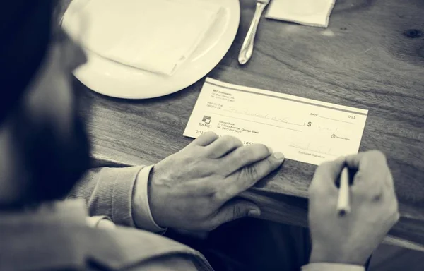 Homme signant un chèque d'argent — Photo