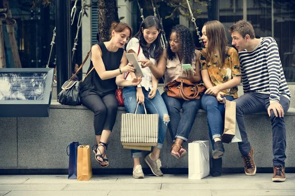 Vänner som sitter nära köpcentrum — Stockfoto