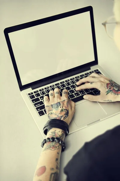 Руки в татуюваннях, що друкуються на ноутбуці — стокове фото