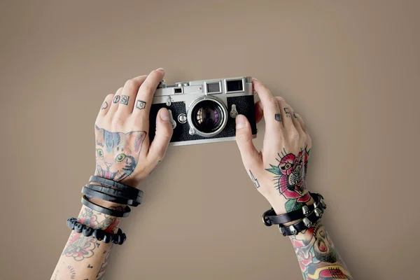 Руки в татуировках держит фотоаппарат — стоковое фото
