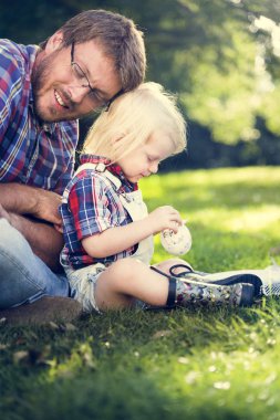 Baba ve oğul çimenlerin üzerinde oturan