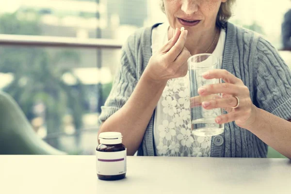 Жінка п'є таблетки — стокове фото