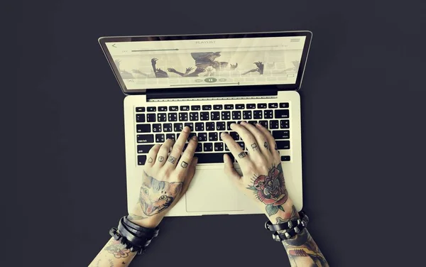 Руки в татуировках, печатающих на ноутбуке — стоковое фото