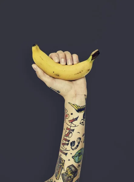 Ruka v tetování drží banán — Stock fotografie