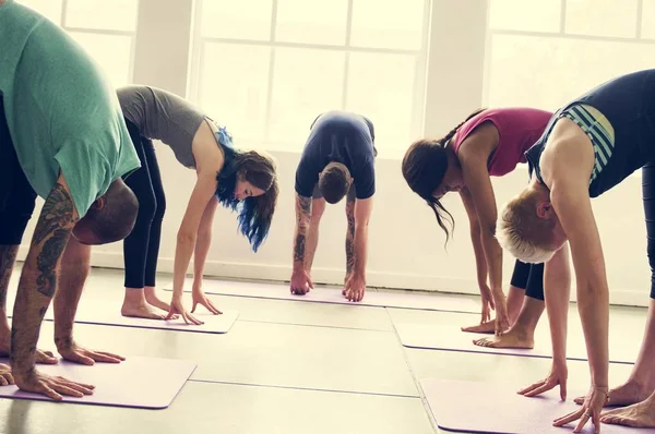 Människor som gör yoga praxis i klass — Stockfoto