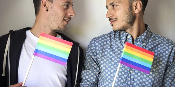 Gay casal segurando arco-íris bandeiras — Fotografia de Stock