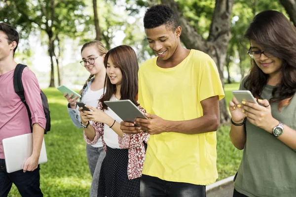 Młodych ludzi chodzenie z cyfrowy gadżety — Zdjęcie stockowe