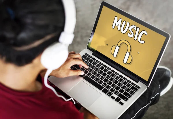 Людина використовує ноутбук і прослуховує музику — стокове фото