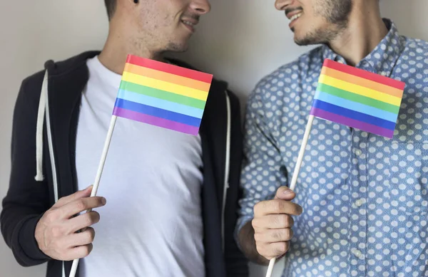 Gay casal segurando arco-íris bandeiras — Fotografia de Stock