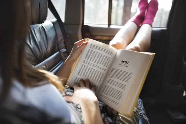 Flicka läsebok i bil — Stockfoto