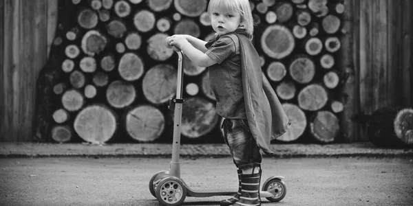 Menino super-herói usando Scooter — Fotografia de Stock