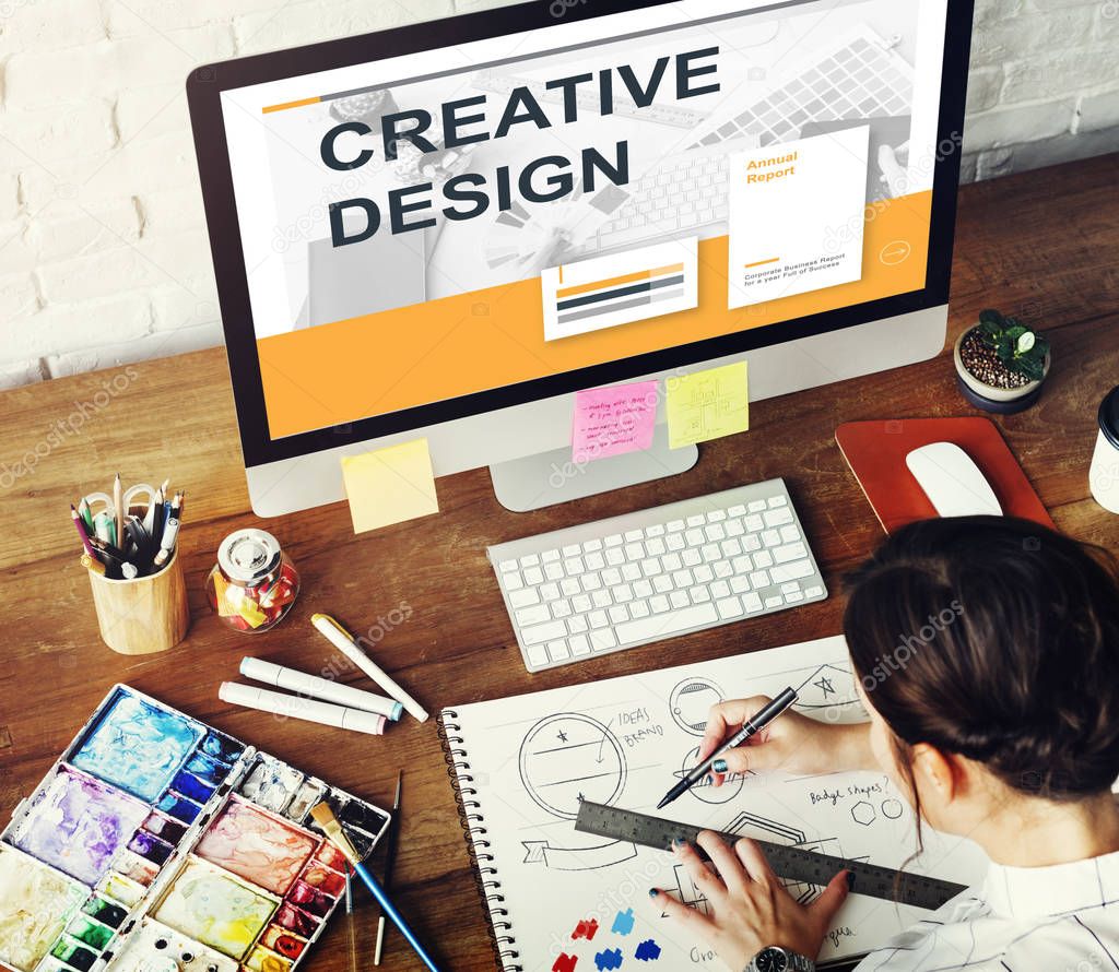 Woman working in art studio, workplace table with colorful paint, art tools, keyboard, graphic designer concept, monitor screen with text: Creative Design