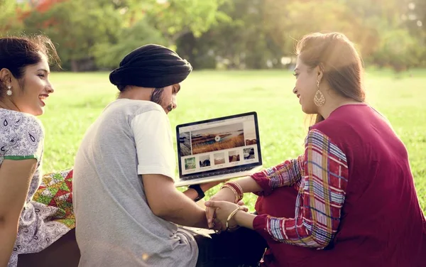 Indiska vänner utomhus använder laptop — Stockfoto