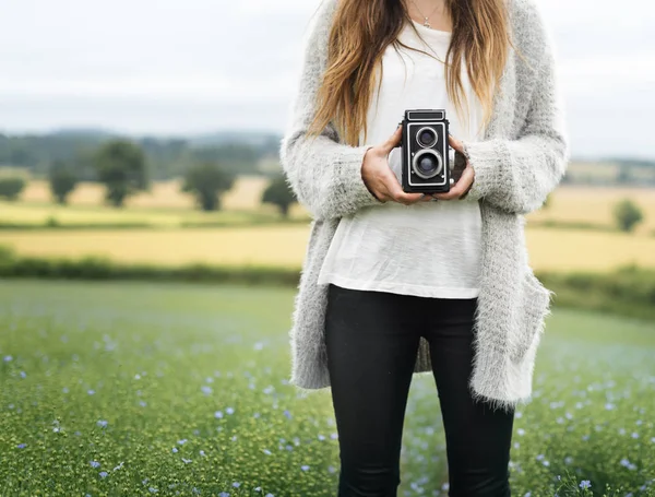 Frau hält Kamera im Feld — Stockfoto