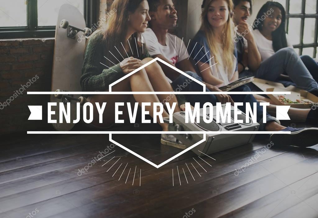 Group of diversity friends sitting on floor and eating pizza, listening music and smiling, text: Enjoy Every Moment