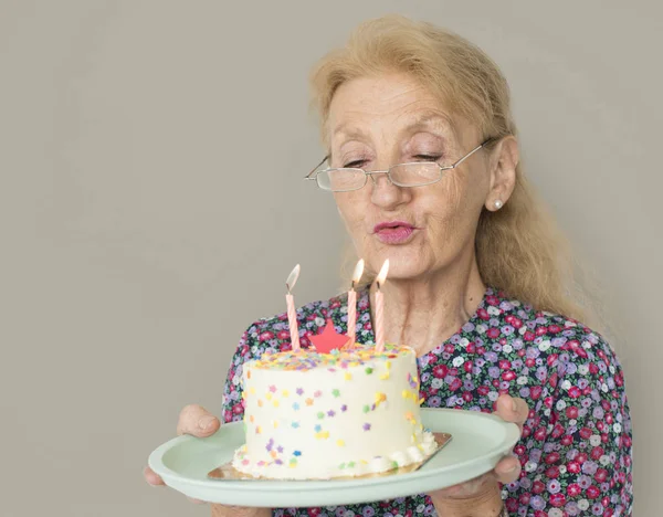 Sênior mulher soprando velas — Fotografia de Stock