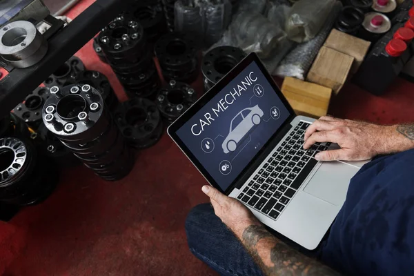 Mechanik samochodowy korzysta z laptopa w garażu — Zdjęcie stockowe