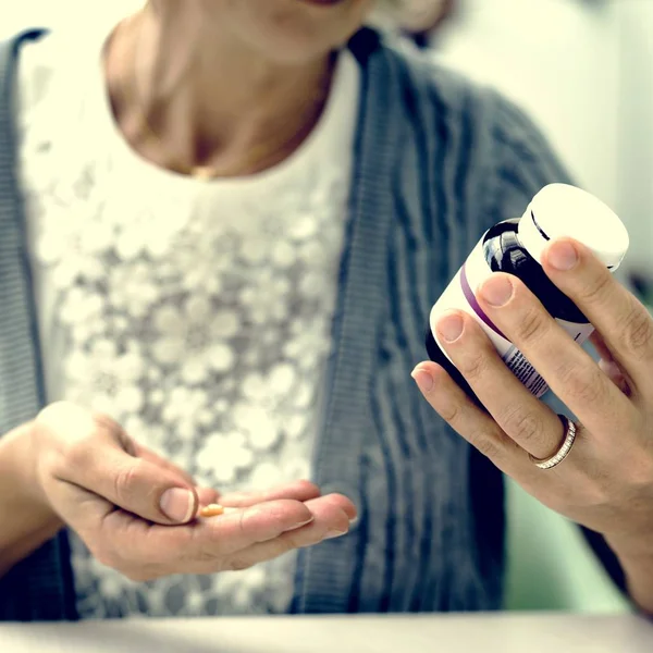 Senior woman talking pills — Stock Photo, Image