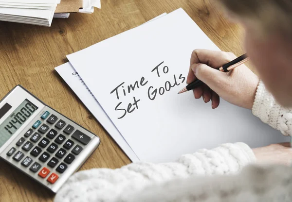 Person writing and using calculator — Stock Photo, Image