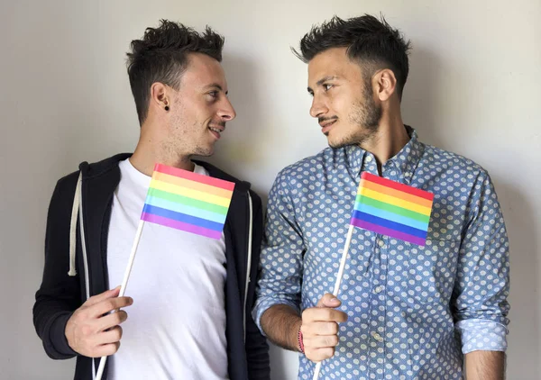 Homosexuální pár drží duhové vlajky — Stock fotografie