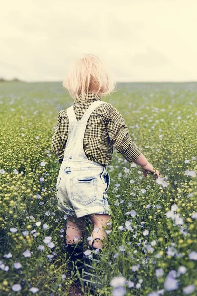Junge geht im Blumenfeld spazieren — Stockfoto