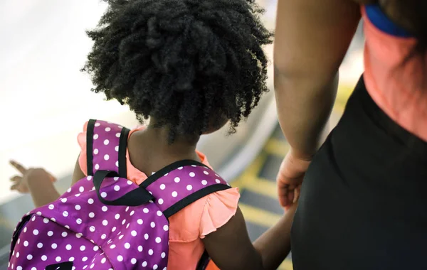 Girl with mom standing on moving staircase — Stock Photo, Image