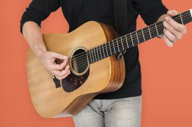 Adam akustik gitar çalıyor.