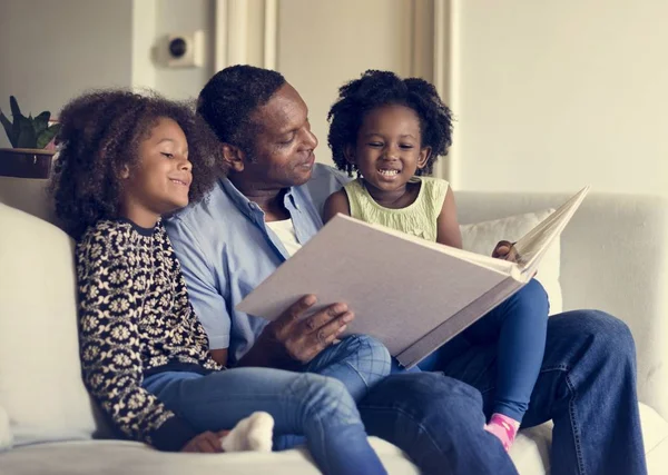 Padre e hijas mirando álbum de fotos — Foto de Stock