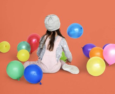 Balonlarla oturan küçük kız