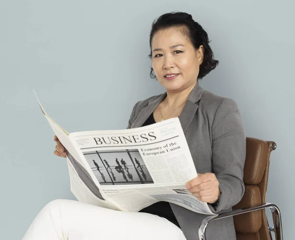 Азиатская женщина читает газету — стоковое фото