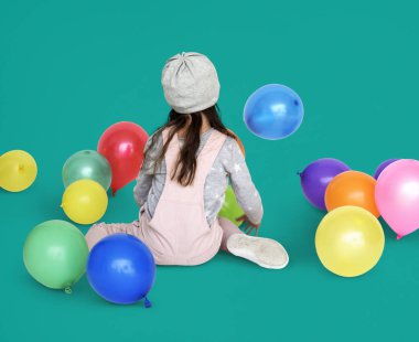 Balonlarla oturan küçük kız