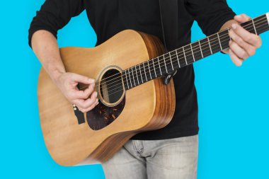 Adam akustik gitar çalıyor.