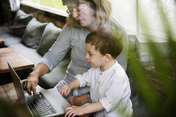 Бабушка использует ноутбук с внуком — стоковое фото