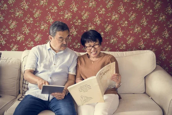 Couple reading brosure on sofa — Stock Photo, Image