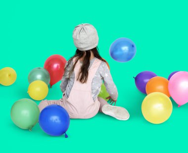 Balonlarla oturan küçük kız